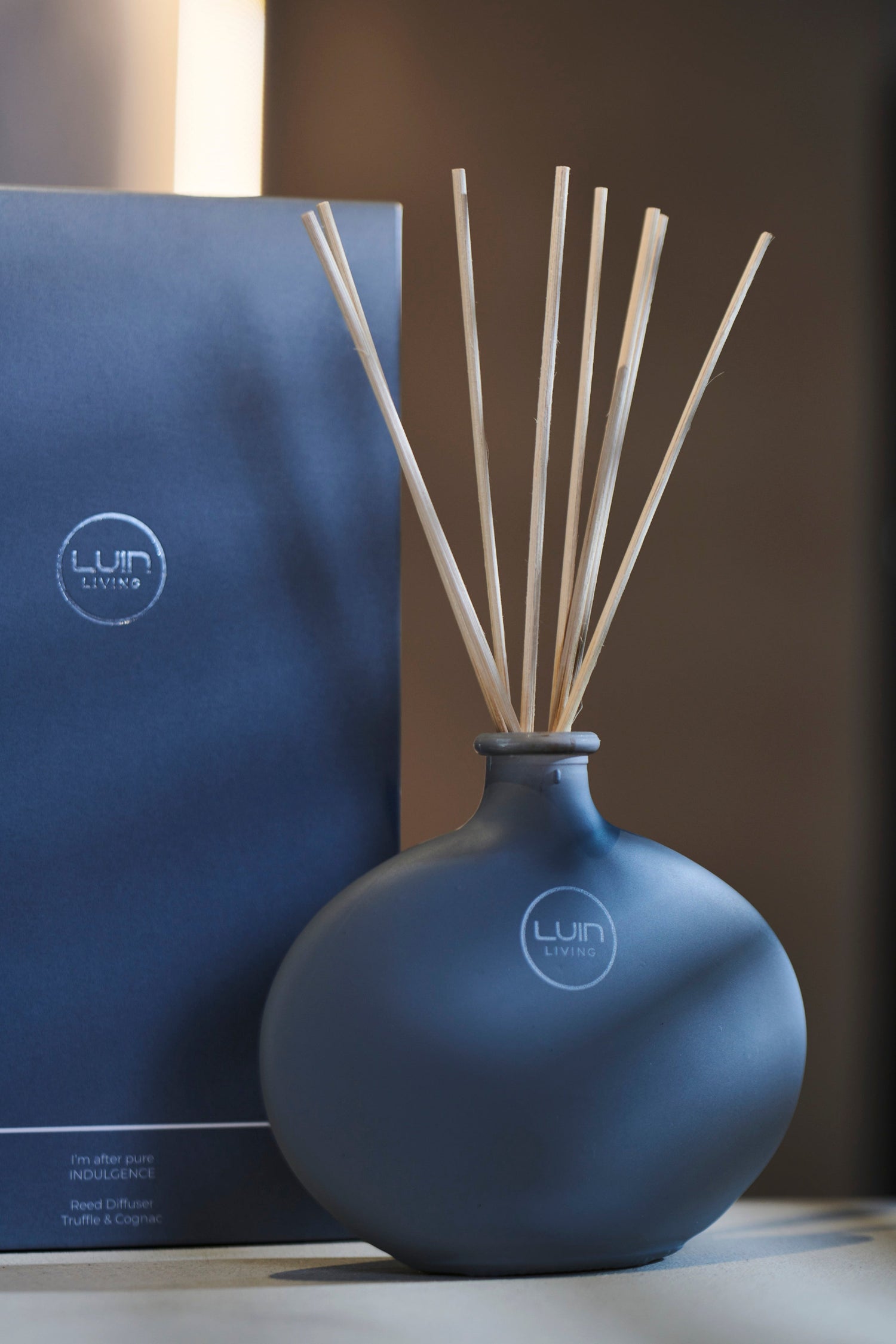 Granite diffuser bottle with sticks and packaging on a neutral background