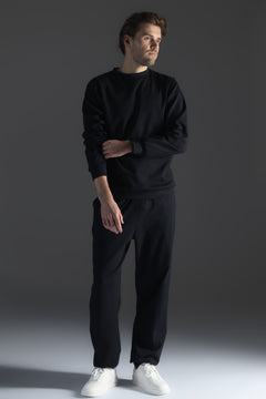 Man wearing a black outfit with white shoes on a gray background