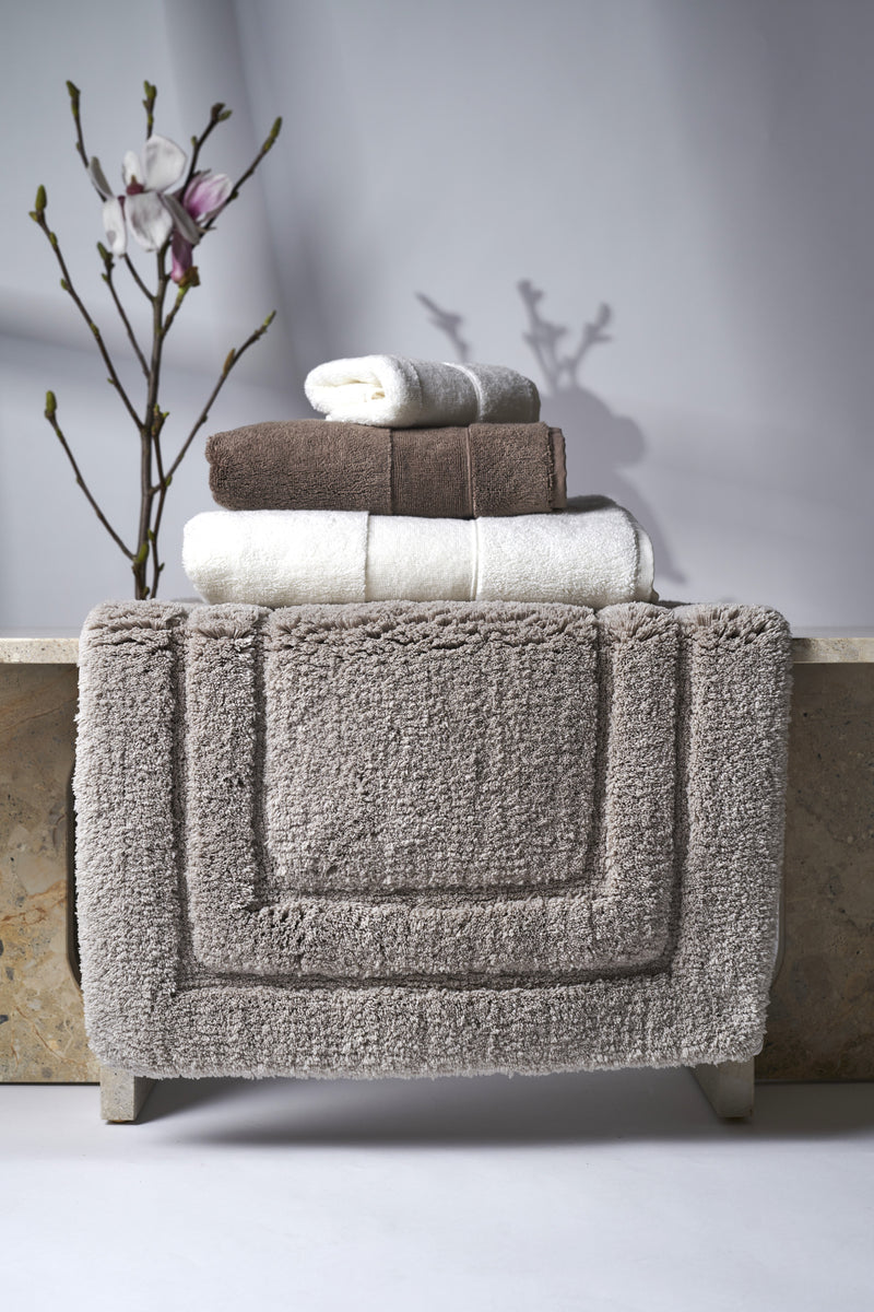 Stack of towels on a textured surface with a branch and flowers in the background