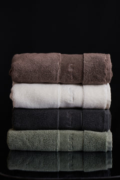 Stack of folded towels in brown, white, black, and green on a black background